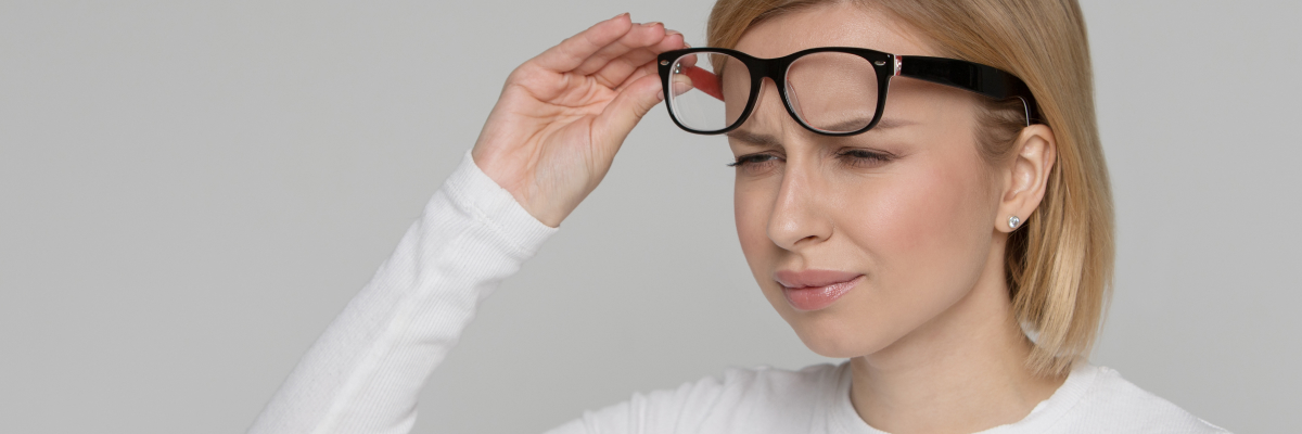 A woman lifting up her glasses with vertigo